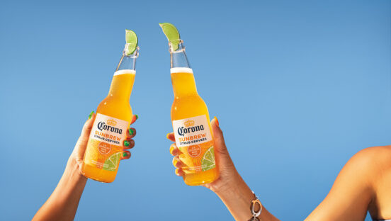 two-hands-holding-corona-sunbrew-bottles-aginast-blue-sky.